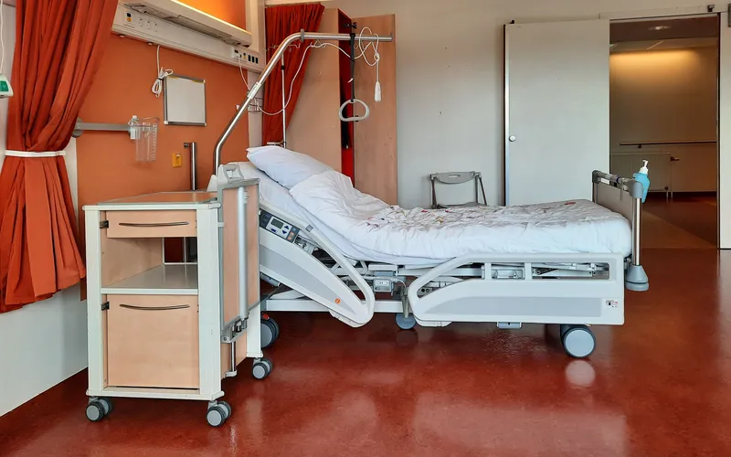 Chambre de clinique avec un lit médicalisé et un rideau orange
