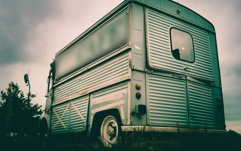 Fourgon vintage aménagé en food truck sous un ciel nuageux