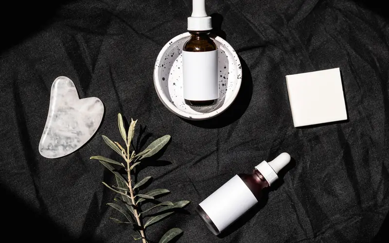 Flacons de sérum et pierre de massage sur tissu noir
