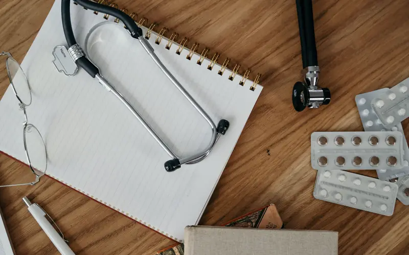 Stéthoscope, bloc-notes et plaquettes de comprimés sur un bureau